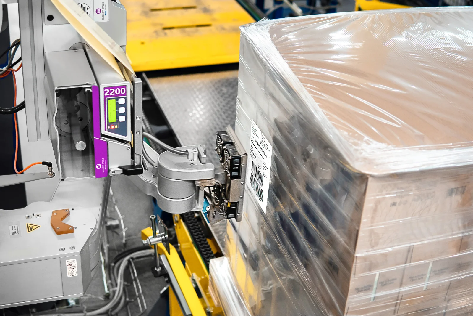 Sistem Print & Apply Markem-Imaje 2200 care aplică o etichetă logistică GS1 pe un palet înfoliat